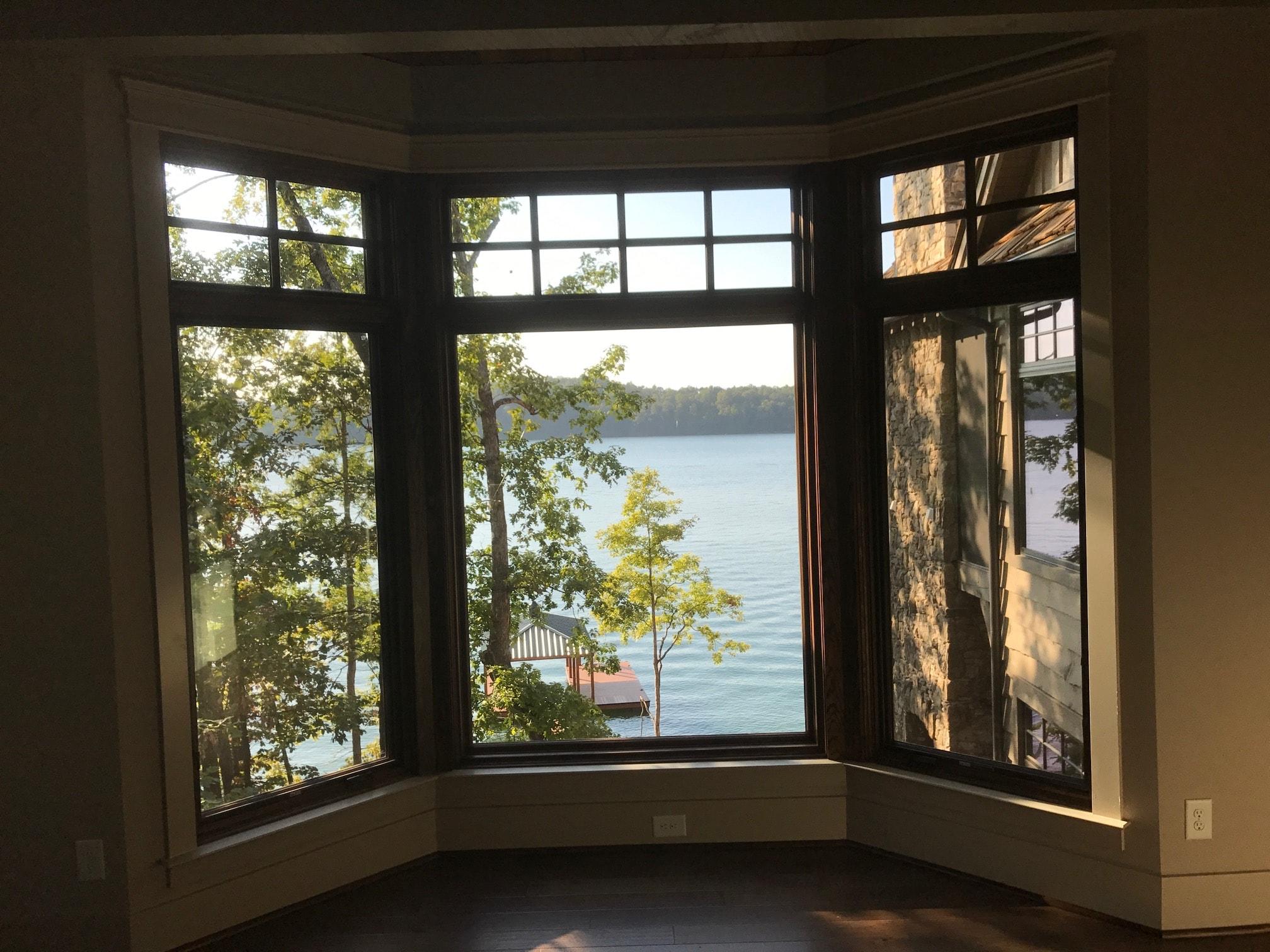 Bay window seat looking over the lake to a dock, with a stone chimney visible through the right-hand light.