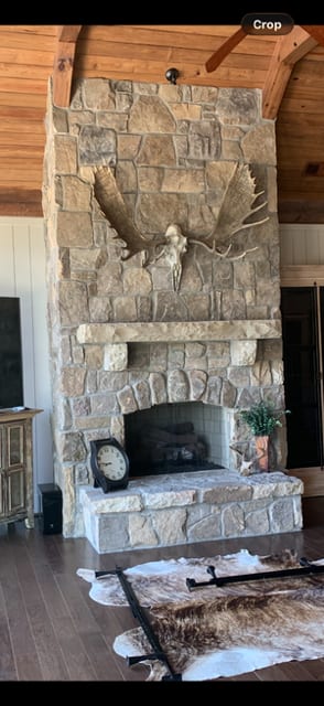 Stone fireplace carried the full height of a vaulted room, with an arched firebox, thick stone mantel and hearth laid in the same stone.